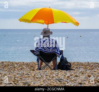 Lyme Regis, Dorset, Regno Unito. 10 settembre 2020. UK Weather: Una donna si siede sotto un ombrellone luminoso e colorato godendo il caldo sole di settembre nella località balneare di Lyme Regis oggi. Credit: Celia McMahon/Alamy Live News Foto Stock