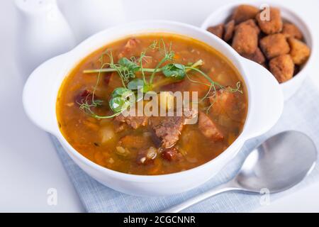 Zuppa di piselli con carne, salsiccia affumicata, germogli di piselli e crostini. Piatto tradizionale russo. Cucina domestica. Primo piano, messa a fuoco selettiva. Foto Stock