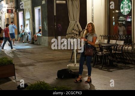 Gdansk, Polonia del Nord - 15 agosto 2020: Una musicista femminile che suona trombetta di strumenti musicali nel centro della città Foto Stock