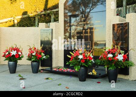 Fiori posati intorno alla base di un memoriale di guerra il giorno di Anzac. Memorial Park, Tauranga, Nuova Zelanda, aprile 25 2018 Foto Stock