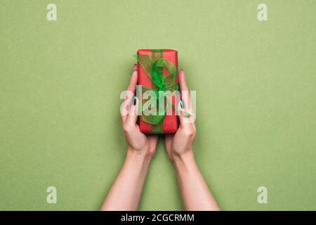 Mani femminili che tengono il regalo avvolto in carta rossa Foto Stock