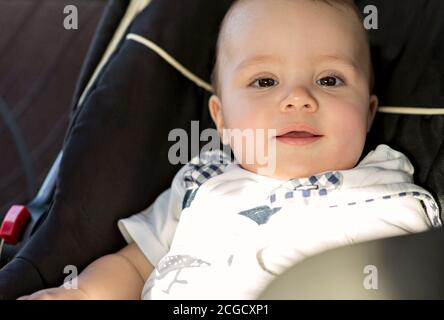 Piccolo bambino in un posto auto in macchina. Tiro dritto. Il bambino guarda la macchina fotografica. Foto Stock