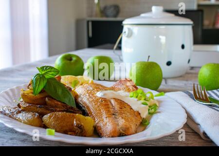 fresco un filetto di salmone fritto fatto in casa con patate arrosto e. salsa di tatar servita su un piatto ovale bianco e una a. tavolo - pronto a mangiare Foto Stock