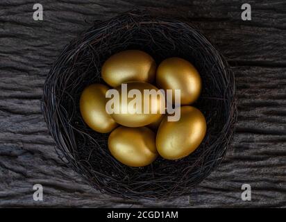 Uova d'oro in un nido sul vecchio tavolo di legno Foto Stock