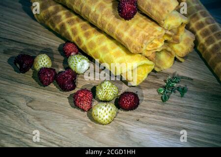 Waffle dorati, fragole bianche e rosse su sfondo di legno. Colazione per tè o caffè. Cibo sfondo. Foto Stock