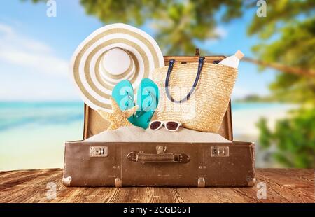 Bagagli retrò con accessori estivi per le vacanze in spiaggia collocati su tavole di legno. Concetto di vacanza estiva e di viaggio. Foto Stock