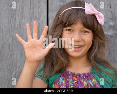 Carino misto-razza ragazza piccola (Asia orientale / caucasica) mostra con la sua mano destra il segno cinese per il numero 5 (serie di foto: Immagine n. 5 di 10). Foto Stock