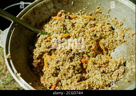 Cucina di gustoso pilau con carne in una grande caldaia fuori. Cibo di strada. Primo piano. Foto Stock