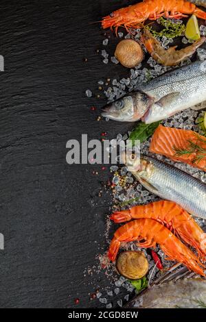 Pesce fresco, cozze, gamberi, pesce, bistecca di salmone, sgombro e altri conchiglie serviti su pietra nera Foto Stock