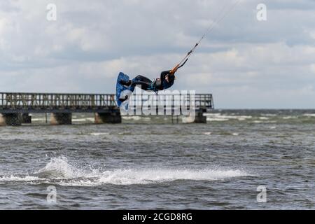 Malmo, Svezia - 23 agosto 2020: Un kitesurfer salta in alto in acqua in una giornata ventosa in cui molte persone cogliano l'opportunità di praticare sport acquatici Foto Stock