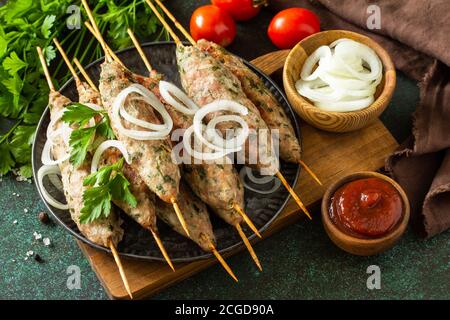 Kebab turco. Kebab Kofta fatti in casa su uno spiedino con verdure e salsa su uno sfondo di pietra o ardesia. Foto Stock