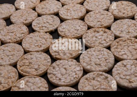 Distribuzione del modello di cracker di riso. Cracker rotondi di riso, sparsi su uno sfondo nero. Design frontale o prospettico. Fotografia low-key. Foto Stock