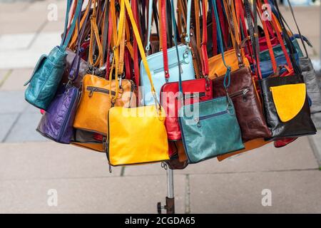 Borse in pelle colorate e luminose per la vendita su un mercato commercianti stallo nella città di Bath, Inghilterra, Regno Unito Foto Stock