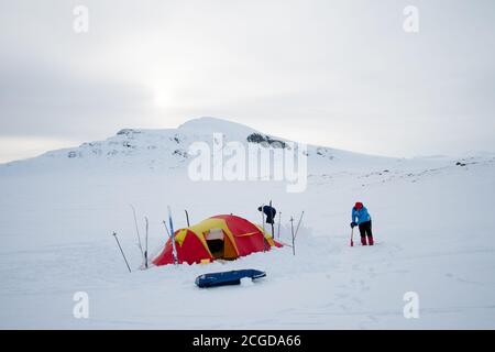 Giovane coppia che prepara il campo invernale sulle montagne norvegesi di Jotunheimen Foto Stock