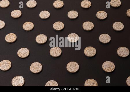 Distribuzione del modello di cracker di riso. Cracker rotondi di riso, sparsi su uno sfondo nero. Design frontale o prospettico. Fotografia low-key. Foto Stock