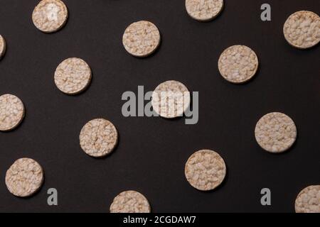 Distribuzione del modello di cracker di riso. Cracker rotondi di riso, sparsi su uno sfondo nero. Design frontale o prospettico. Fotografia low-key. Foto Stock