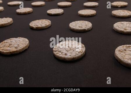 Distribuzione del modello di cracker di riso. Cracker rotondi di riso, sparsi su uno sfondo nero. Design frontale o prospettico. Fotografia low-key. Foto Stock