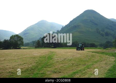 Trattore sul campo con i Wainwrights 'Middle Dodd' e 'High Hartsop Dodd' vicino a Brothers Water nel Lake District National Park, Cumbria, Inghilterra. Foto Stock