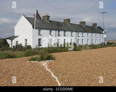 Una linea di conchiglie bianche conduce dalla fila di cottage a Shingle Street attraverso le desolate rive di ghiaia sulla costa di Suffolk. Foto Stock