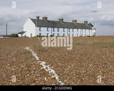 Una linea di conchiglie bianche conduce dalla fila di cottage a Shingle Street attraverso le desolate rive di ghiaia sulla costa di Suffolk. Foto Stock