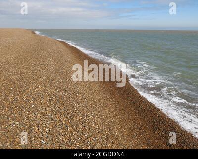 Una riva di ghiaia sulla costa orientale di Suffolk dove le fredde acque del Mare del Nord lambiscono la costa. Foto Stock