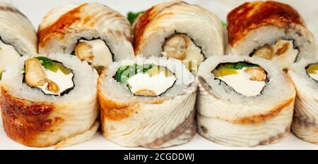 Rotolo di sushi con anguilla e insalata di chuka su un piatto bianco, sushi giapponese classico. Cucina tradizionale giapponese con maki. Deliziosi pezzi di sushi. per il menu del ristorante. copyspace. Foto Stock