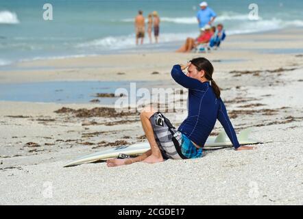 HOLMES BEACH, ANNA MARIA ISLAND, FL / USA - 4 ottobre 2013: Surfista che riposa sull'isola di Anna Maria approfittando del wav più grande del normale Foto Stock