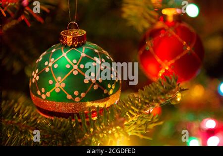 Ornamenti natalizi appesi in un albero di Natale illuminato in abete balsamo. Foto Stock