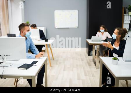 Dipendenti in Business persone che parlano con Social Distancing e faccia Maschere Foto Stock