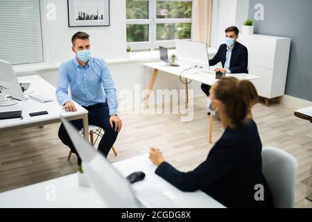 Dipendenti in Business persone che parlano con Social Distancing e faccia Maschere Foto Stock