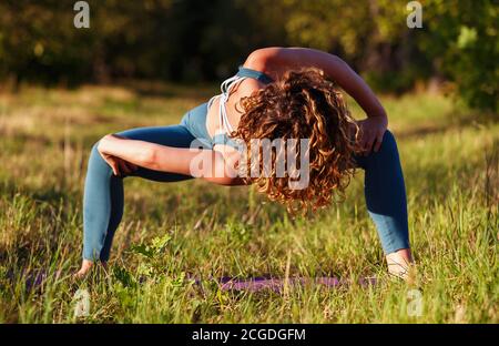 Giovane donna sportiva fa lo yoga routing su tappetino all'aperto in Green  Park.Beautiful ragazza bianca in 20 con capelli ricci che indossano tuta da  fitness blu che fa yog Foto stock - Alamy