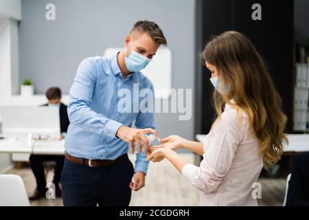 Pulizia delle mani all'ingresso dell'ufficio con igienizzatore antisettico Foto Stock
