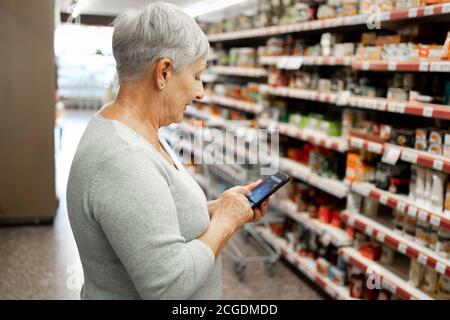 Donna anziana caucasica con shopping di capelli bianchi nel supermercato Foto Stock