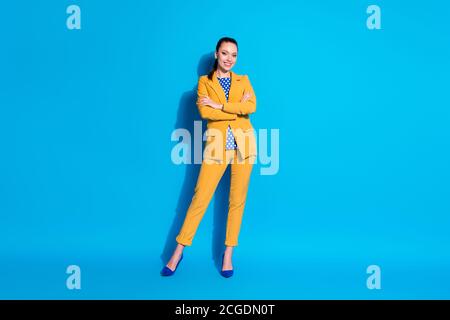 Foto a lunghezza intera di abbastanza sicuro elegante ragazza dentro bright suit che tiene le braccia ripiegate isolato sfondo blu Foto Stock