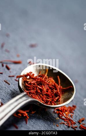 Lo zafferano in un cucchiaio su uno sfondo scuro, il fuoco selettivo, macro shot, profondità di campo Foto Stock