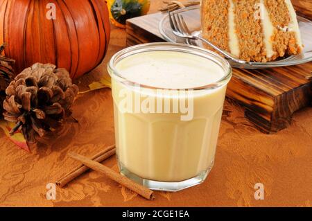 Un bicchiere di uovo di zucca speziato con una fetta di torta di carote Foto Stock