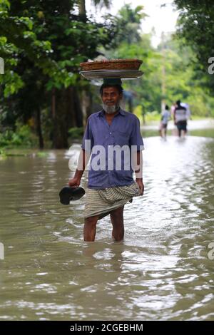 Un uomo cammina attraverso l'acqua allagata a Dohar a Dhaka, Bangladesh il 20 luglio 2020. Ogni anno milioni di persone colpite da inondazioni a causa di forti piogge e fiumi in eccesso nelle parti nord-orientali e nord-occidentali del Bangladesh. Molte persone sono morte, sfollate, hanno perso i raccolti, le case, hanno sofferto di cibi e acqua potabile pura durante l'alluvione monsonica. Foto Stock