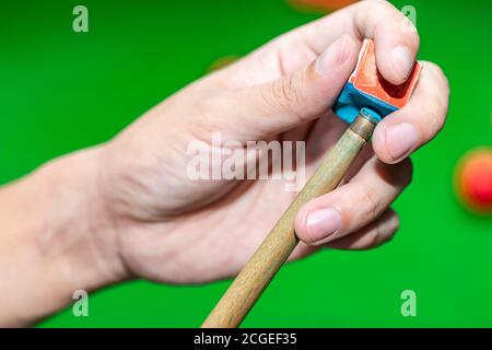 Primo piano giocatore di mano snooker utilizzando gesso strofinare una cue. Foto Stock