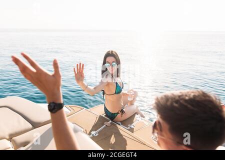 Giovane coppia di persone caucasiche che si agghiacciano sul moderno yacht deck. Vela il mare. Foto Stock