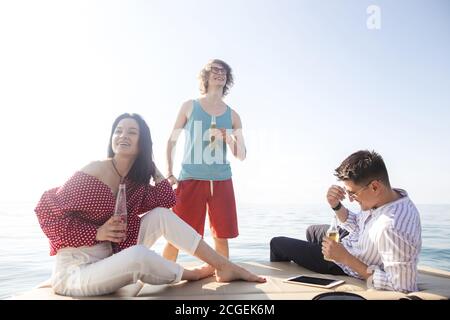 Amici rendendo la barca parte avendo divertimento bere birre e ridere insieme nel mare di vela Foto Stock