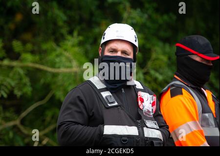 Denham, Buckinghamshire, Regno Unito. 8 Settembre 2020. Un agente di Enforecement del team nazionale di viction e una guardia di sicurezza HS2 vicino al campo. Un giovane protettore dell'albero femmina scalò un albero questa mattina destinato ad essere tagliato da HS2. Una nuova infortunio che ha impedito agli attivisti ambientali e ai protettori degli alberi di terra nel Denham Country Park è stata concessa all'HS2. Il controverso collegamento HS2 High Speed Rail è impostato per danneggiare o distruggere 108 boschi antichi. Credito: Maureen McLean/Alamy Foto Stock