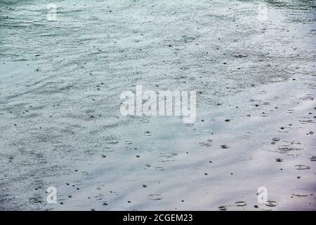 Gocce di pioggia che cadono sulla superficie dell'acqua. Foto Stock