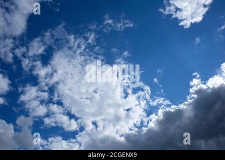 nuvole bianche contro il cielo blu. sole luminoso dietro le nuvole vista dal basso. sfondo naturale cielo durante il giorno d'estate Foto Stock