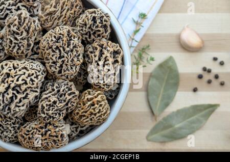 Funghi porcini primaverili commestibili appena raccolti in una ciotola in ceramica su un tagliere con spezie. Primo piano, messa a fuoco selettiva. Foto Stock
