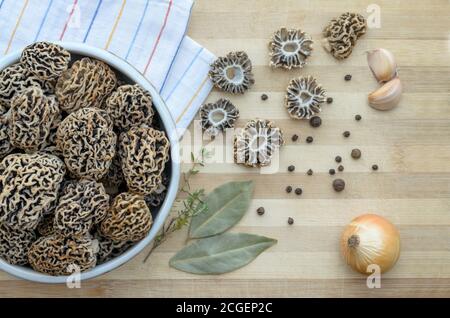 Funghi porcini primaverili commestibili appena raccolti in una ciotola in ceramica su un tagliere con spezie. Primo piano, vista dall'alto. Foto Stock