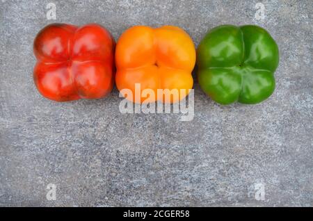 Peperoni multicolore su sfondo grigio con spazio per la copia. Primo piano, vista dall'alto Foto Stock