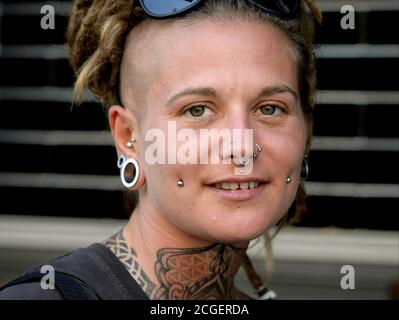 Giovane donna caucasica con piercing viso, tatuaggi e dreadlock pone per la macchina fotografica. Foto Stock