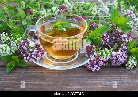 Tazza di tè caldo appena fatto alle erbe con menta e origano su un vecchio tavolo di legno. Concetto di uno stile di vita sano. Foto Stock