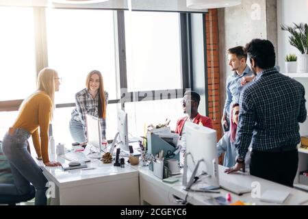 Giovani designer creativi multietnici al lavoro in un ufficio internazionale. Spazio di lusso, pieno di luce naturale e sole. Foto Stock