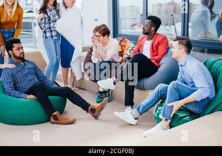 amici multietnici seduti all'aperto nell'area lounge sul tetto del business center discutere le loro vacanze doings Foto Stock
